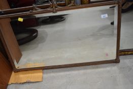 An antique coppered brass framed mantle mirror having torchere ends with studded frame, approx width