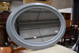 A modern moulded plastic oval wall mirror, in grey, approx. 74cm x 54cm , currently strung in