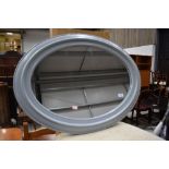 A modern moulded plastic oval wall mirror, in grey, approx. 74cm x 54cm , currently strung in