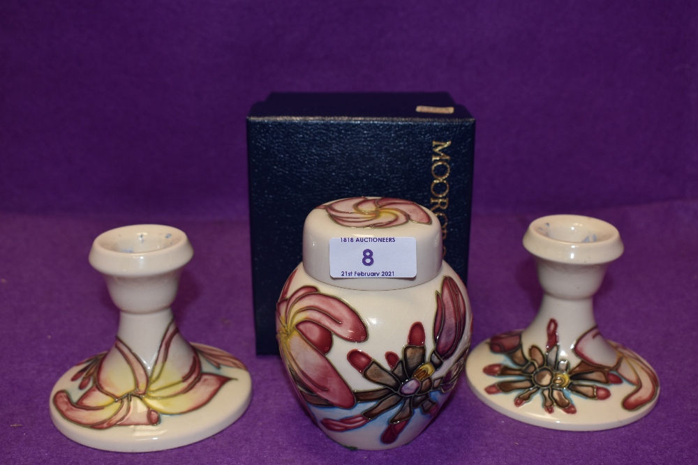 A pair of candlesticks and a ginger jar having cream ground with pink magnolia like design,