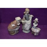 A Lladro figurine, Girl with Lamb 4835 and two Nao figurines, Girl with Duck in Basket and Girl with