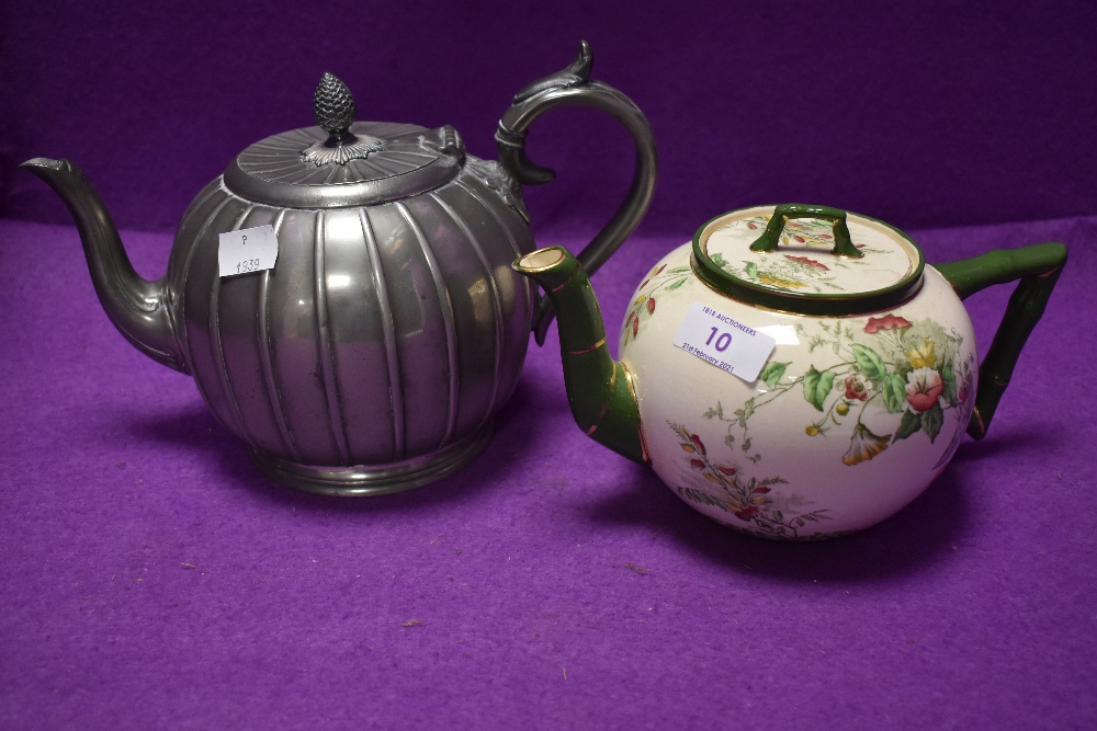 Two teapots, one pewter having intricate design the other having Doulton Burslem cream ground with