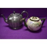 Two teapots, one pewter having intricate design the other having Doulton Burslem cream ground with