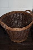 A large wicker log basket with handles.