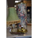 A brass candle stick holder, a table lamp with shade,an umbrella/stick or similar lidded storage