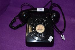 A vintage black rotary dial plastic telephone.