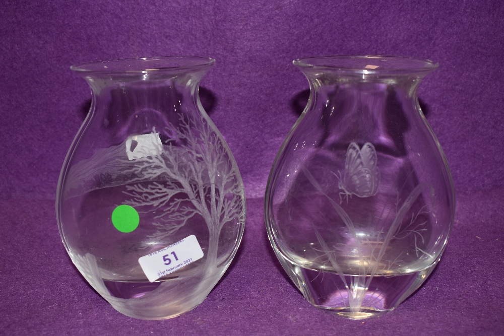 A pair of glass vases having etched designs one with butterfly design the other tree and landscape