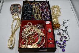 A material covered jewellery case containing a selection of beaded necklaces, strings of simulated