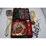 A material covered jewellery case containing a selection of beaded necklaces, strings of simulated