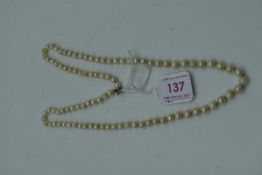 A string of cultured pearls of even form having a gold clasp. approx 25'