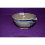 An earthen ware spouted bowl having blue delft design having stamp to base possibly reading Poole