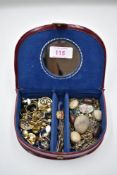 A small travel jewellery case containing a selection of clip earrings, pendants and bar brooches