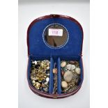 A small travel jewellery case containing a selection of clip earrings, pendants and bar brooches