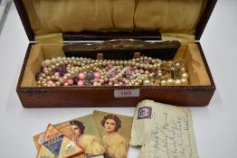 A vintage case containing a selection of strings of simulated pearls, silver plated comb and