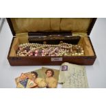 A vintage case containing a selection of strings of simulated pearls, silver plated comb and