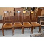 A set of four early 20th century golden oak dining chairs having rail backs, later dralon