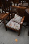 A vintage stripped low seat easy chair with canework back