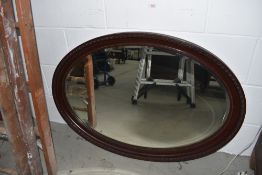 An antique over mantle mirror oval shape having carved frame work