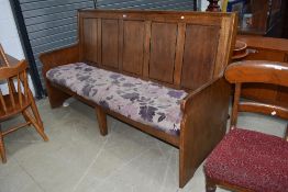A traditional golden oak settle, having five panels to back and solid ends, width approx. 196cm