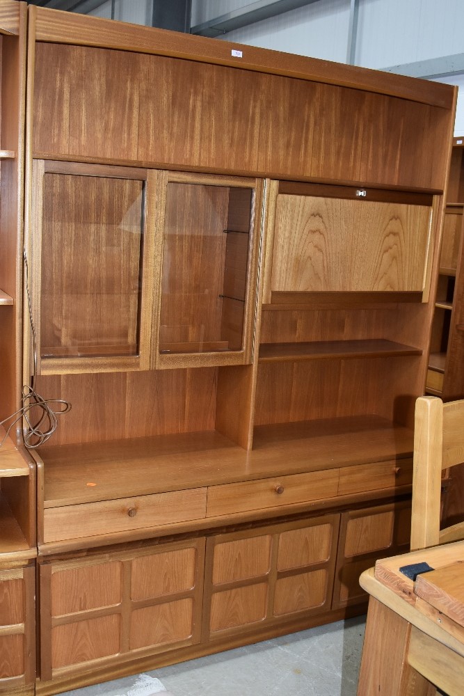 A vintage teak Nathan wall unit, having glazed display and lockable cocktail section, over triple