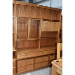 A vintage teak Nathan wall unit, having glazed display and lockable cocktail section, over triple