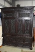 An impressive period dark stained press or cloak cupboard having extensive carved detailing under