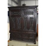 An impressive period dark stained press or cloak cupboard having extensive carved detailing under