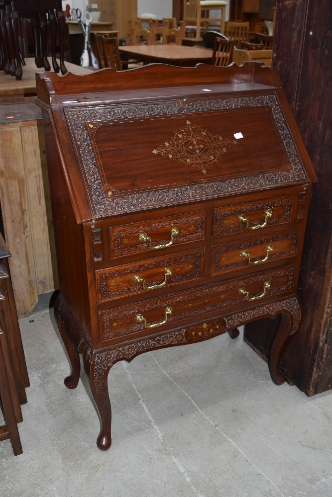 An Oriental style hardwood bureau with brass inlay and carved door and drawer borders, width