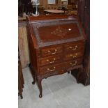 An Oriental style hardwood bureau with brass inlay and carved door and drawer borders, width