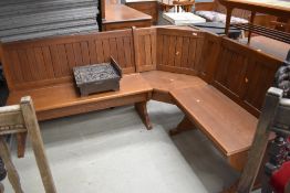 An ecclesiastical corner bench or form of three parts having storage seats in a golden oak