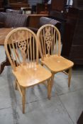 A pair of wheel back chairs having solid seats