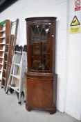 A reproduction Regency style corner display having cupboard under