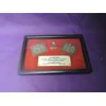 A framed WW2 Memorial consisting of two shoulder badges, cap badge and plaque reading In Memoriam