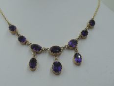 A ten stone heat treated amethyst necklace having seven graduated stones with three drops on a fixed