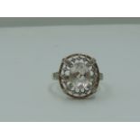 A lady's dress ring having a morganite style oval stone within an open border having diamond chip