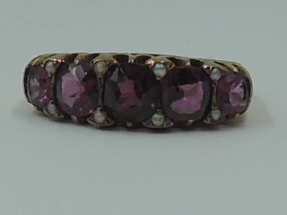 An Edwardian lady's dress ring having five graduated pink stones interspersed by tiny seed pearls in