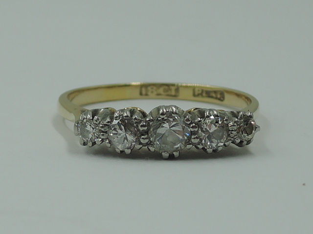 A lady's dress ring having five graduated diamonds in a claw set raised mount on a yellow metal loop