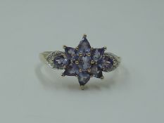 A lady's dress ring having a pale blue paste cluster with diamond chip set shoulders on a yellow