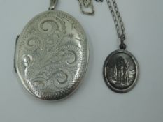 An oval white metal locket stamped silver bk & fnt having engraved scroll decoration on a white