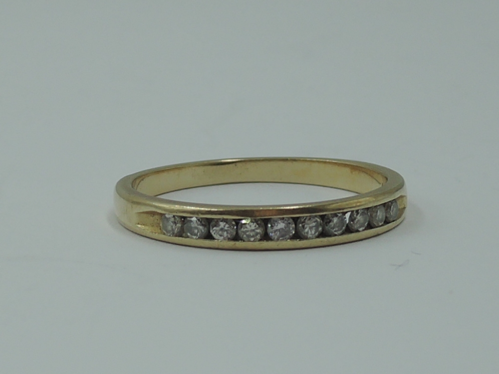 A lady's half eternity ring having ten chanel set diamond chips on a yellow metal loop stamped