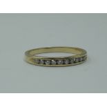 A lady's half eternity ring having ten chanel set diamond chips on a yellow metal loop stamped