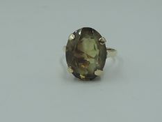 A lady's dress ring having an oversized yellow/brown oval stone in a four claw basket mount on a 9ct