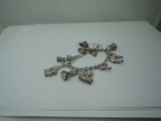 A silver charm bracelet with padlock clasp having eight white metal charms including camel, emu,