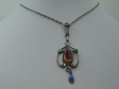 An Edwardian silver pendant of Art Nouveau design having enamelled decoration on a white metal