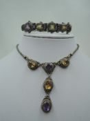 An amethyst and citrine necklace having five stones in decorative silver mounts on a fixed snake