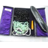 A vintage travel jewellery case containing strings of beads including mother of pearl and seed