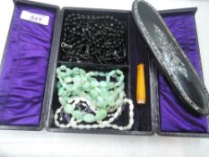 A vintage travel jewellery case containing strings of beads including mother of pearl and seed