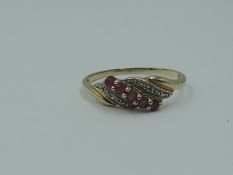 A lady's dress ring having a row of ruby style stones in a swirl illusionary mount on yellow metal