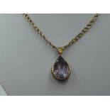 A 9ct gold fancy link chain with a tear drop style amethyst pendant in a yellow metal mount, no
