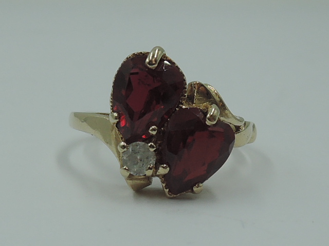 A lady's dress ring having two ruby style teardrop stones in claw set heart mounts with a clear